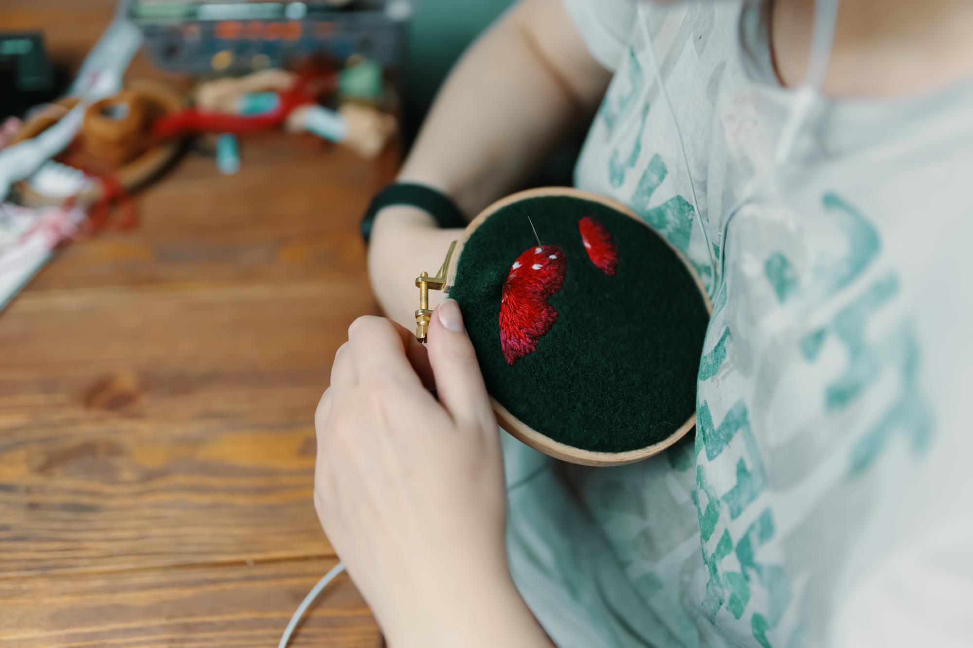 Artist hands guiding embroidery hoop in bright studio